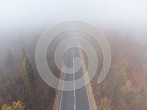 Asphalt road highway in an autumn fog forest aerial view