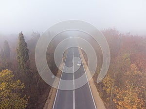 Asphalt road highway in an autumn fog forest aerial view