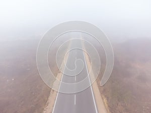 Asphalt road highway in an autumn fog forest aerial view