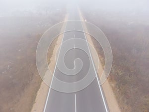 Asphalt road highway in an autumn fog forest aerial view