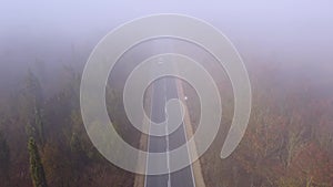 Asphalt road highway in an autumn fog forest aerial view