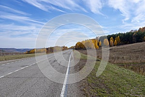 Asphalt road, highway. The road going into the distance, perspective. Colorful autumn countryside landscape. Autumn sunny day