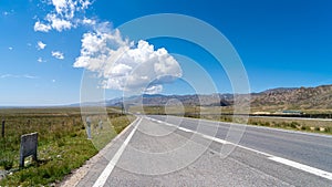 Asphalt road, highway with road markings captured on a bright day with fluffy clouds in the sky