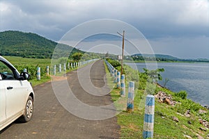 asphalt road beside lake with boundary pillars