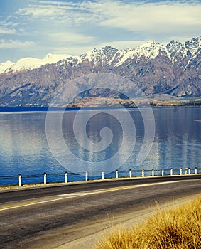 Asphalt Road With Lake And Mountain Range Concept