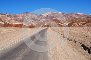 Asphalt road leading through steaming hot landscape of Death Valley National Park, California, USA. Super hot sunny day
