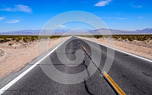 Asphalt road leading through steaming hot landscape of Death Valley National Park, California, USA. Super hot sunny day