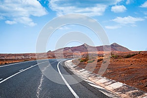 Asphalt road leading to horizon trough the dusty landscape of Boa Vista island.