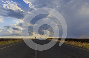 Asphalt road in the mountains on the background of a storm sunset