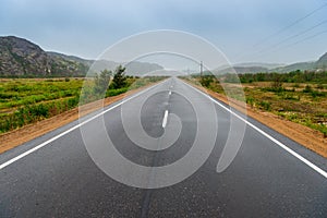 Asphalt road in polar tundra landscape.