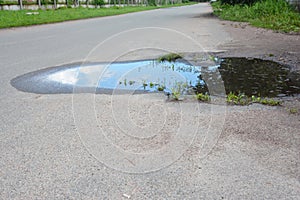 Asphalt road on puddles. Pot hole or pothole image of a broken cracked asphalt pavement