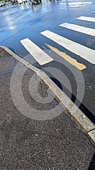 Asphalt road after the rain and crosswalk with reflections