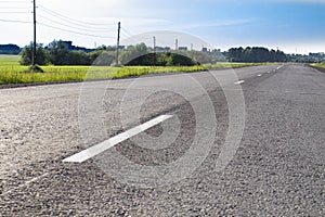 Asphalt road with road markings, evening bright sunlight