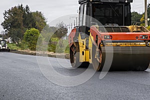 Asphalt road roller with heavy vibration roller compactor press new hot asphalt on the roadway on a road construction