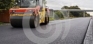 Asphalt road roller with heavy vibration roller compactor press new hot asphalt on the roadway on a road construction