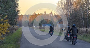 An asphalt road running through the autumn forest. Motorcyclists on historic machines.