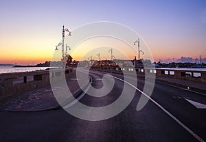 Asphalt road in sea bay leading to old town of Nessebar, Bulgaria, on background of colorful sky