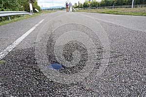 Asphalt road with a small pothole full of rainwater in low angle view. photo