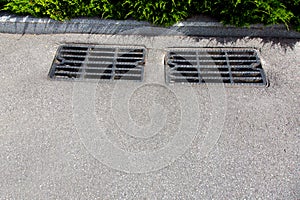 Asphalt road with storm drain sewer grate.