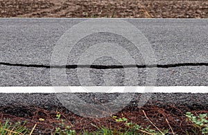 Asphalt road surface cracks near the white line