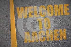 asphalt road with text welcome to Aachen near yellow line