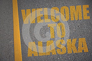 asphalt road with text welcome to alaska near yellow line