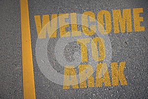 asphalt road with text welcome to Arak near yellow line