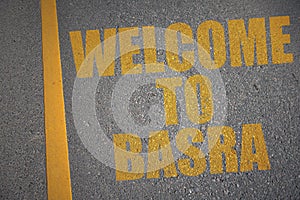 asphalt road with text welcome to Basra near yellow line photo