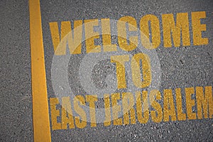 asphalt road with text welcome to East Jerusalem near yellow line