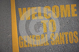 asphalt road with text welcome to General Santos near yellow line