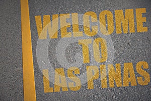 asphalt road with text welcome to Las Pinas near yellow line