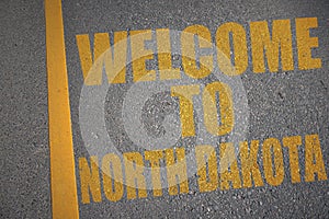 asphalt road with text welcome to north dakota near yellow line.