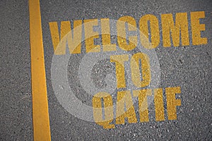 asphalt road with text welcome to Qatif near yellow line photo