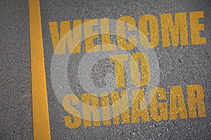 asphalt road with text welcome to Srinagar near yellow line