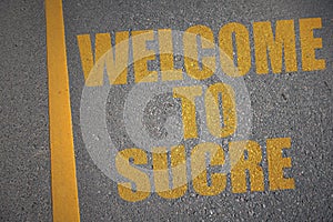 asphalt road with text welcome to Sucre near yellow line