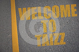 asphalt road with text welcome to Taizz near yellow line