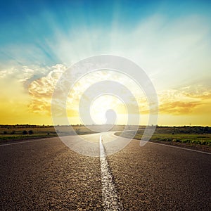 Asphalt road to horizon and sunset in clouds