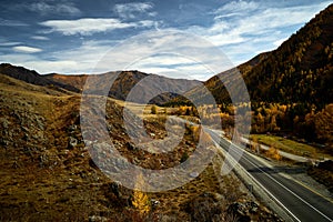 Asphalt road to the mountains of Altai passing through the autumn landscape