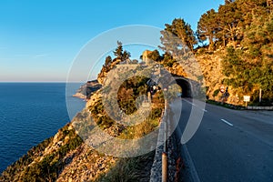 Asphalt road and tunnel in the rock above the sea. Panorama