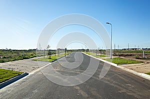 Asphalt road between vacant lands in a new residential suburb. Tarneit, Melbourne, VIC Australia.