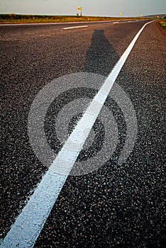 Asphalt road and a white lane in the evening outside the city