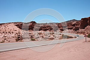 An asphalt road winding down a  desert area