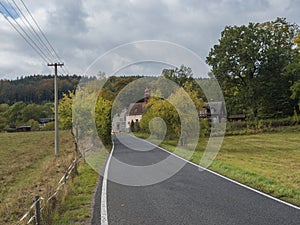 Asphalt road winding in small village Travnik with chapel , country house and cottage in autumn colorful landscape