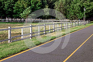 Asphalt road with yellow markings on the side a wooden fence.