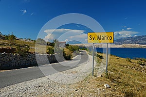 Asphalt road with yellow sign of Sv. Marko settlement northern of Sveta Maria beach in center of Pag Island, northern Dalmatia