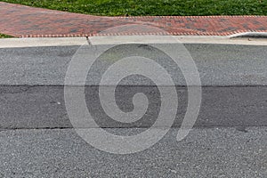 Asphalt roadway with long horizontal strip of newer pavement, brick sidewalk and curb beyond creative copy space