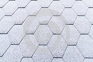 Asphalt roofing shingles texture covered with light snow. House roof shingles covered with frost. Snow covered roof of the house