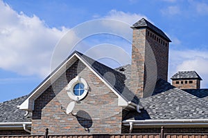 Asphalt shingle. Decorative bitumen shingles on the roof of a brick house.