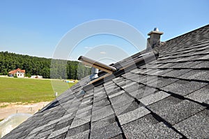 Asphalt shingles roof with open attic skylight window and unfinished roof chimney