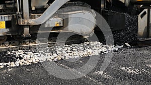Asphalt spreader or asphalt paver on a road construction site close-up.